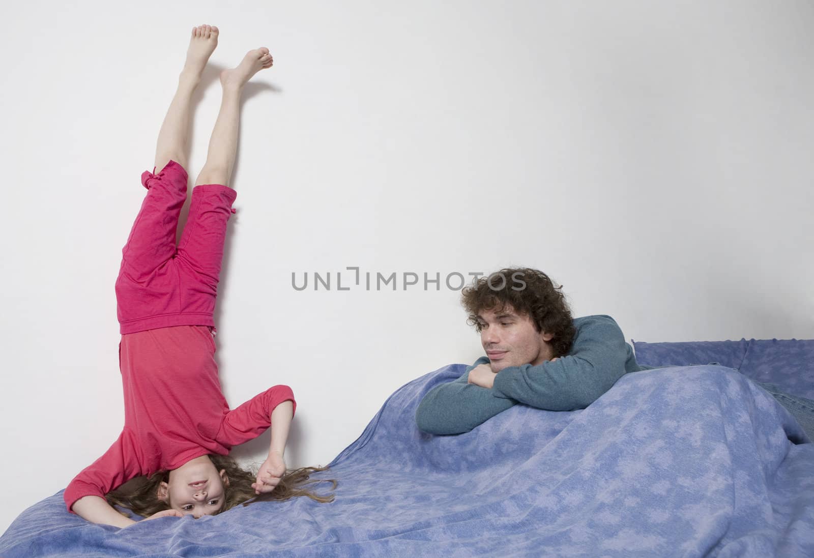 young smiling cute girl standing at head. Upside-down. Father watching it