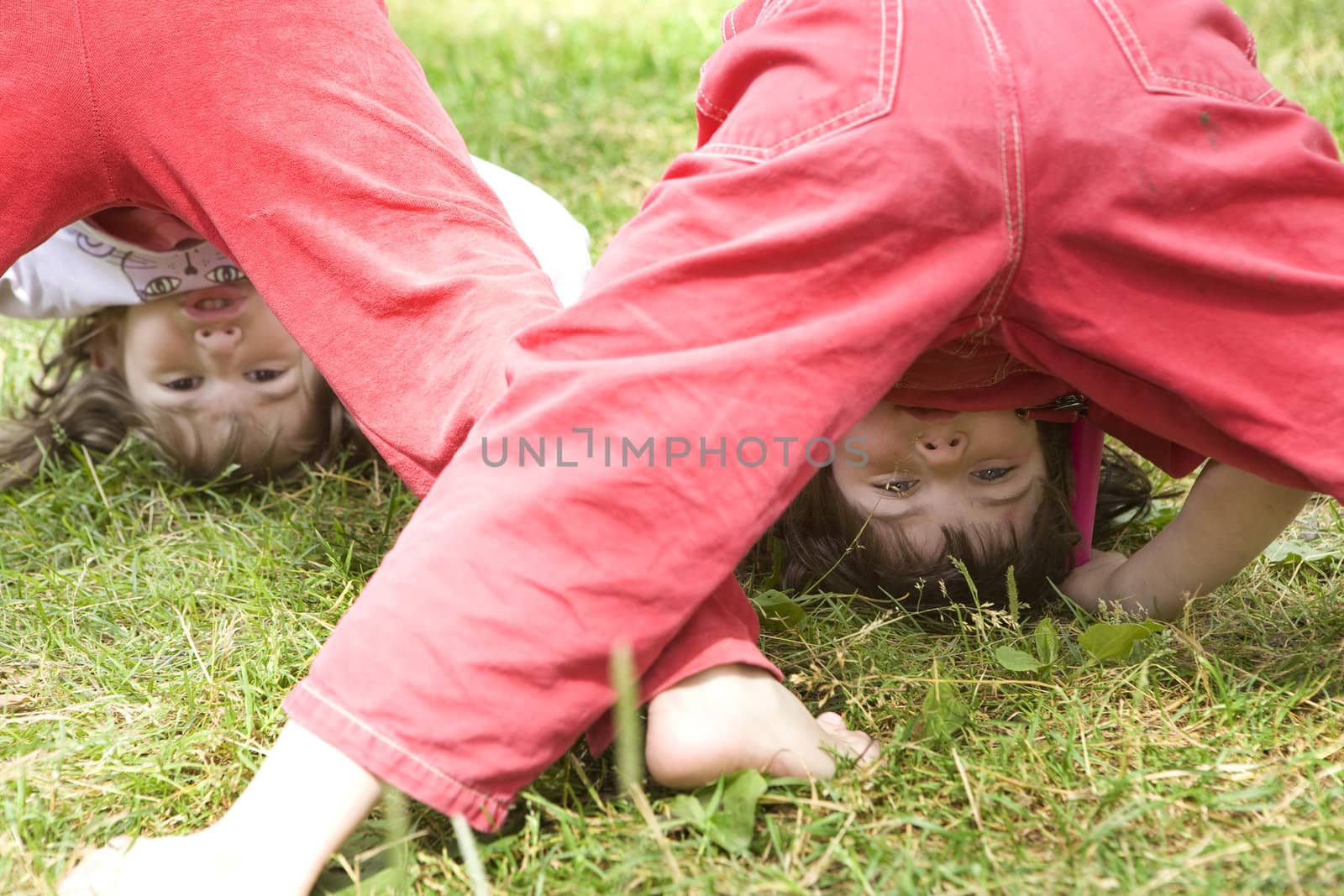 young smiling cute girl standing at head on grass. Upside-down by elenarostunova