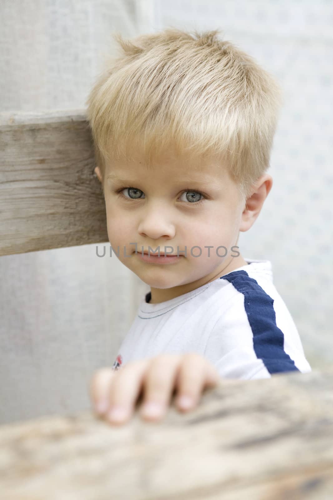 portrait of little serious  five years boy standing at bench
