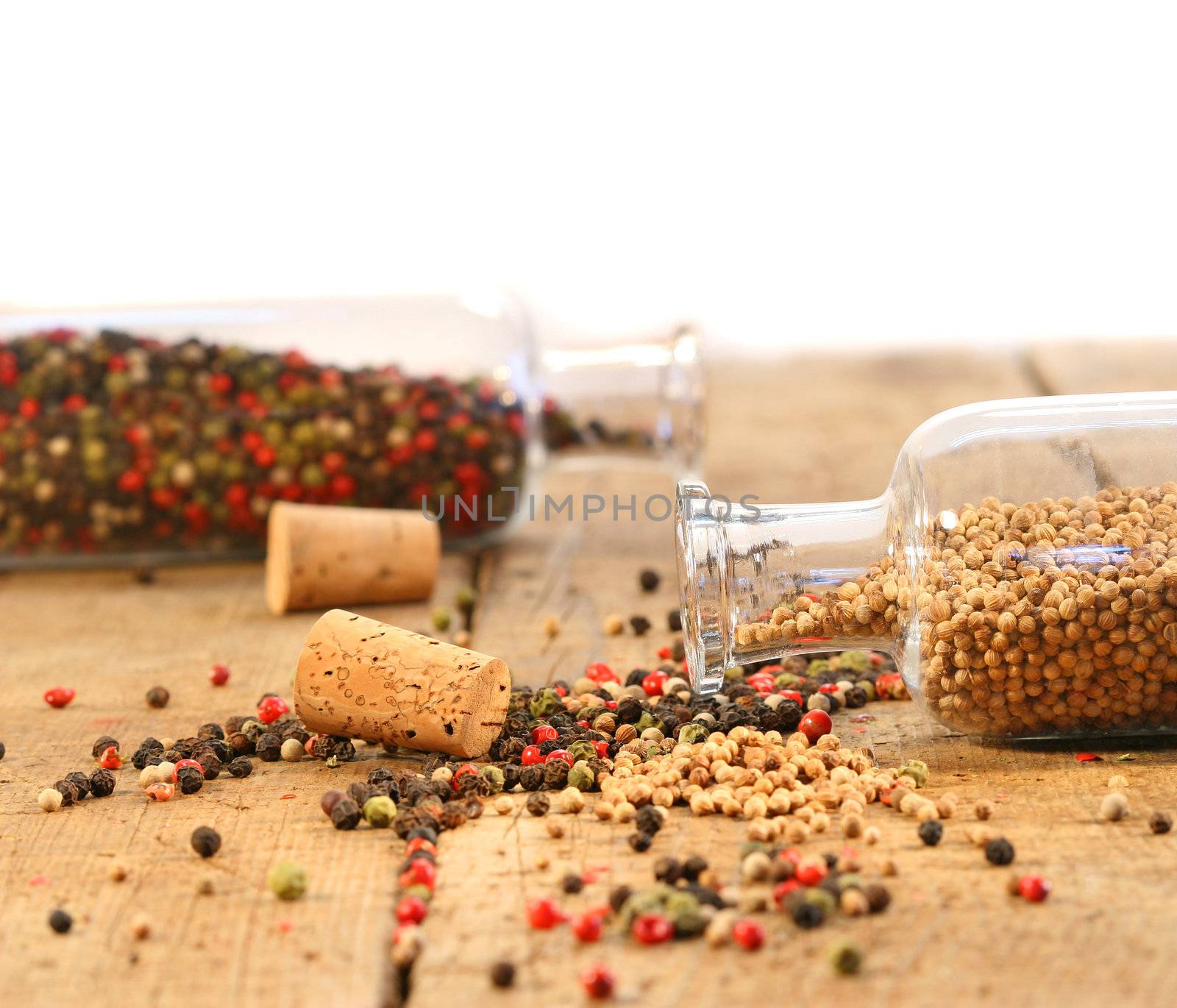 Peppercorns in glass bottles on rustic wood table