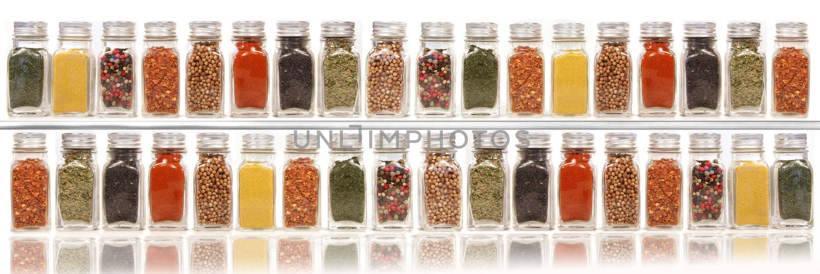 Assorted spices on two layer shelves against white  by Sandralise
