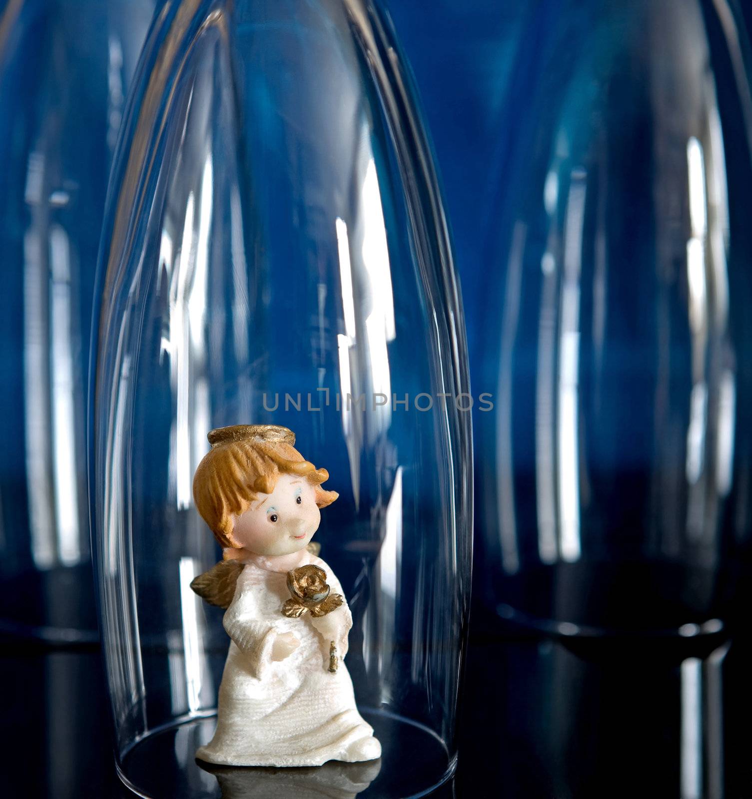 Toy angel between the glass on blue background