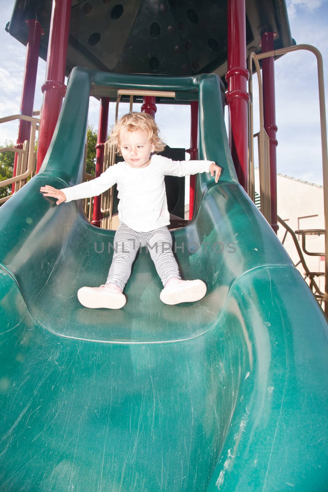 Cute little European toddler girl having fun at the playground in the park.