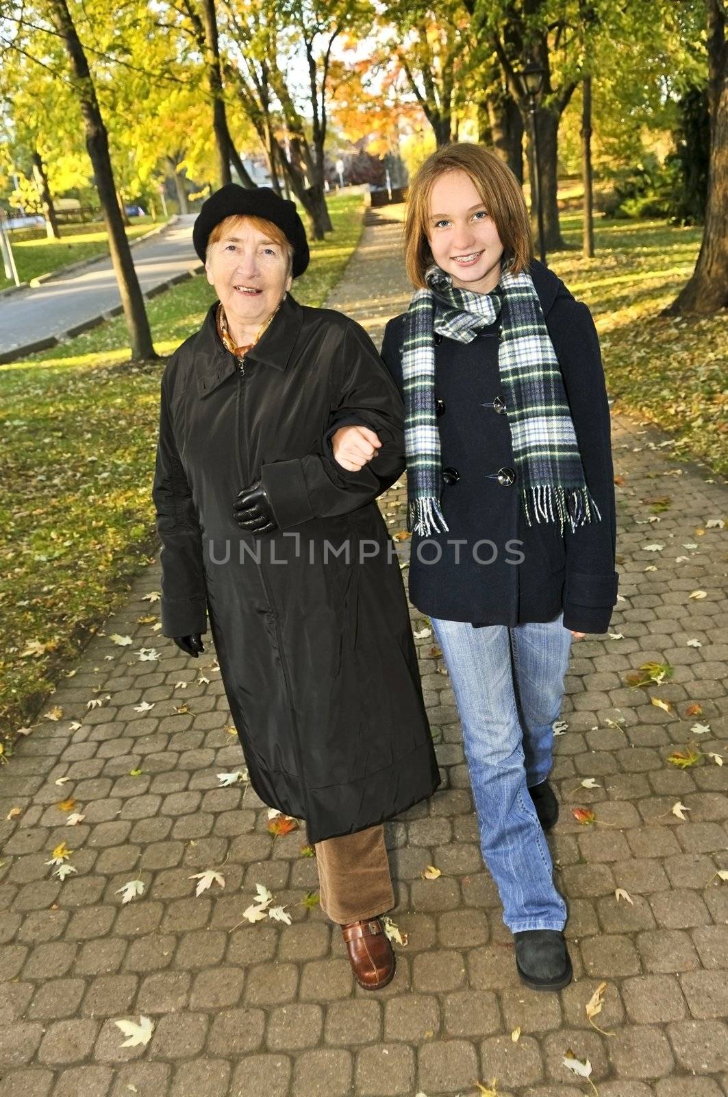 Teen granddaughter walking with grandmother in autumn park