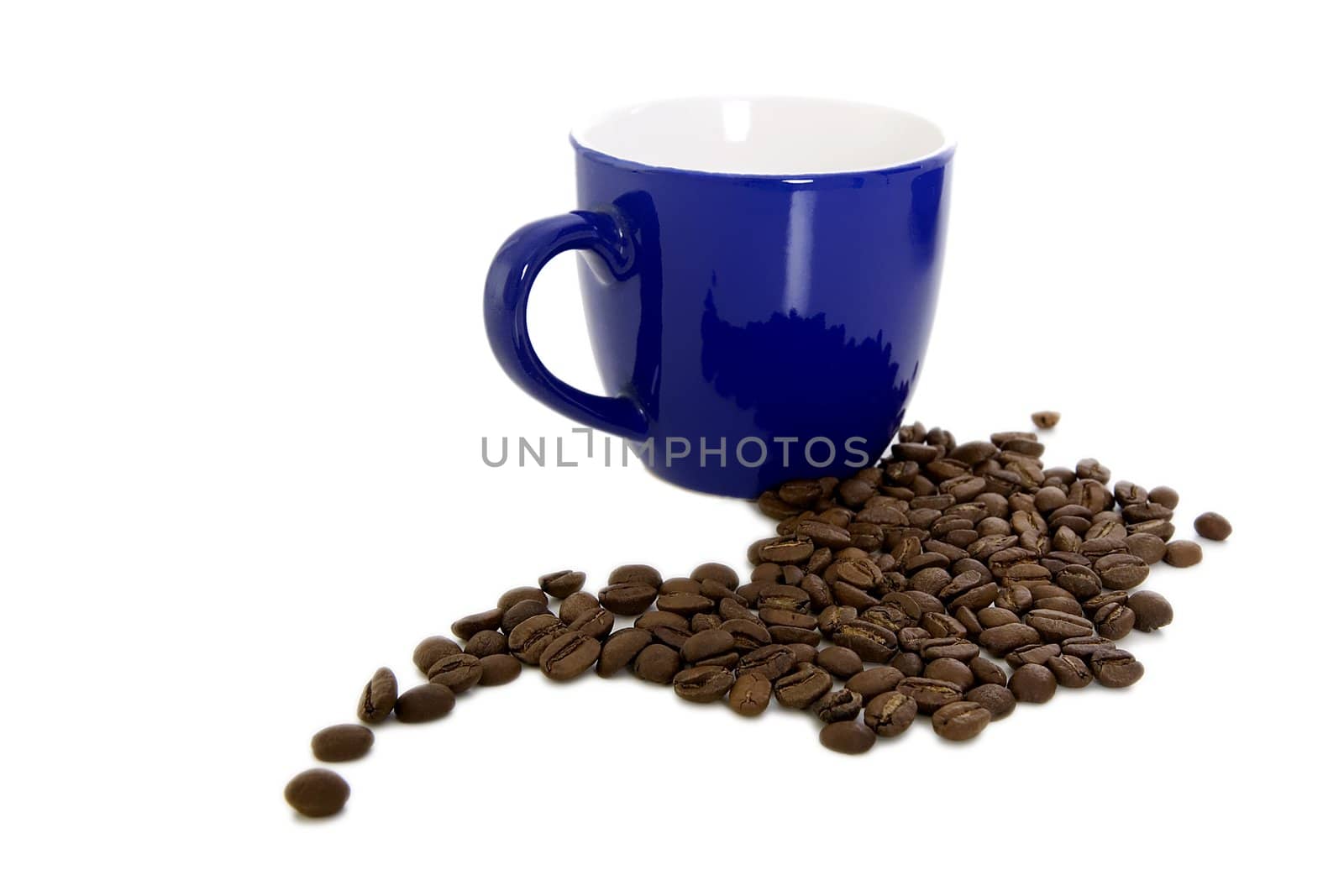 Dark blue mug and scattered coffee on a white background