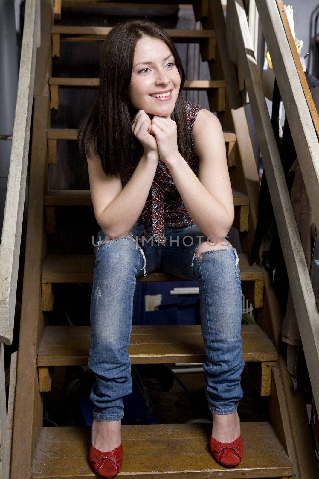 young attractive smiling  girl in jeans having a hole sitting on by elenarostunova
