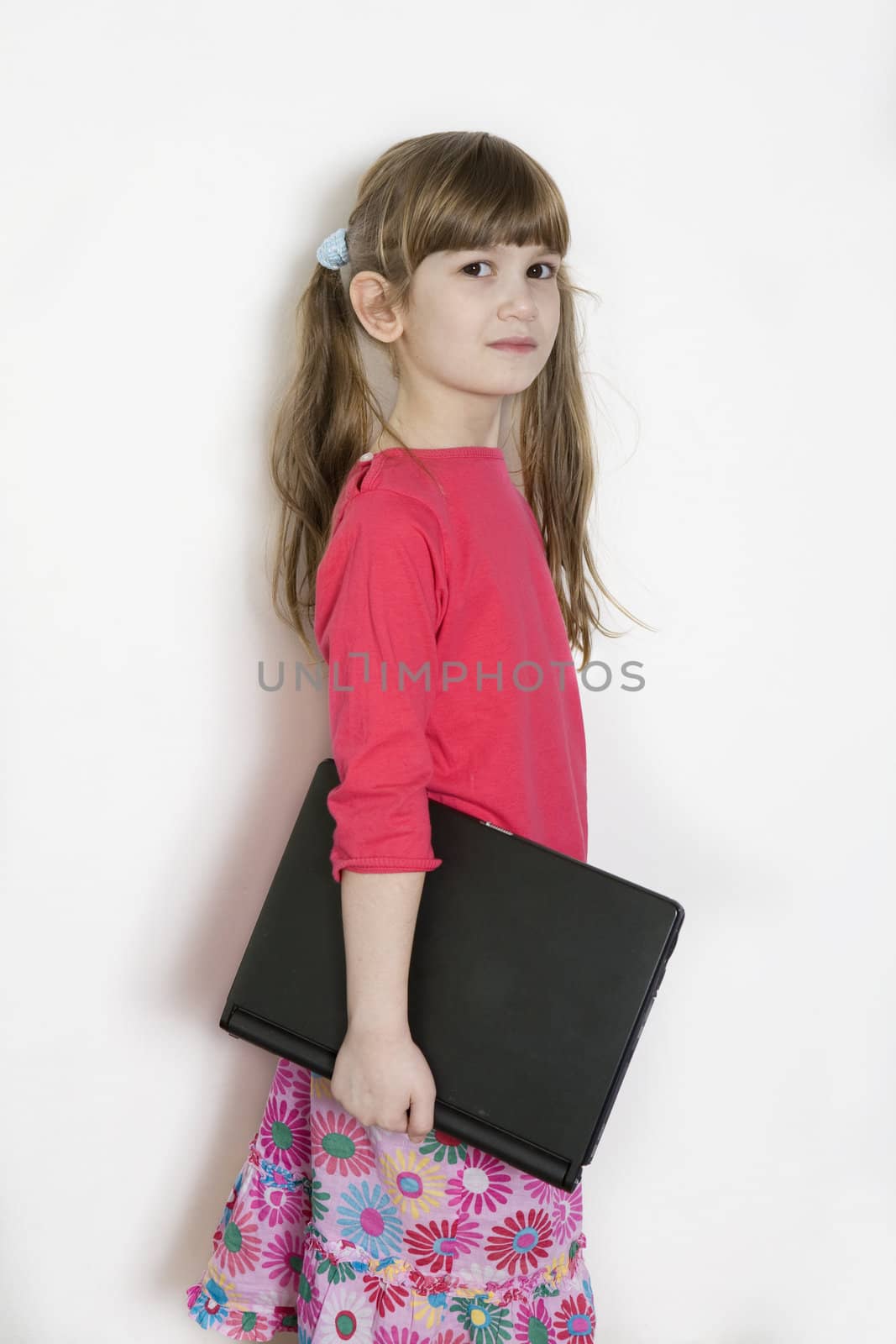 little cute adorable girl with laptop standing at white wall