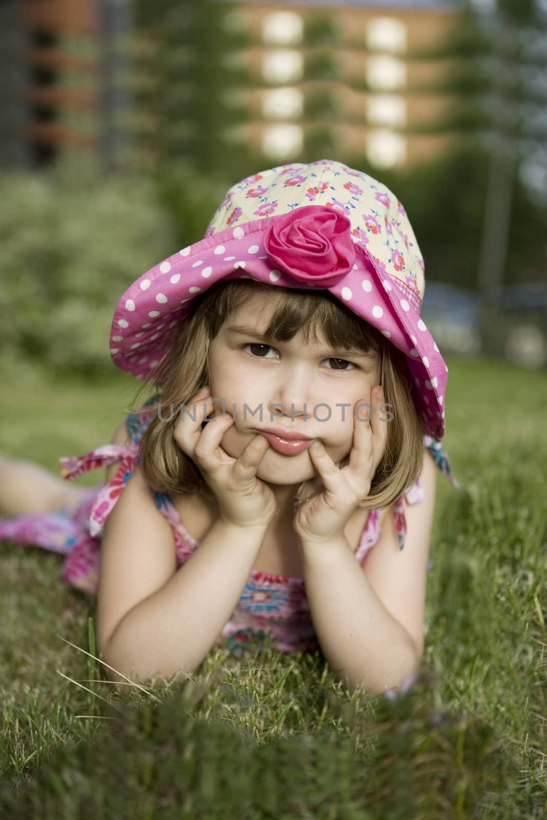 little cute gloomy girl in panama lying on grass