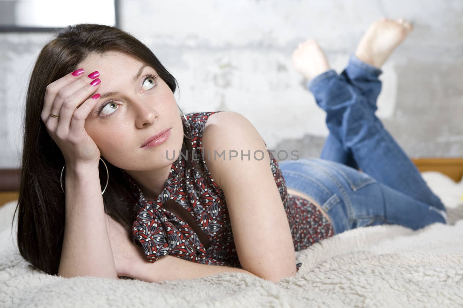 young attractive brunette woman in jeans lying on sofa
