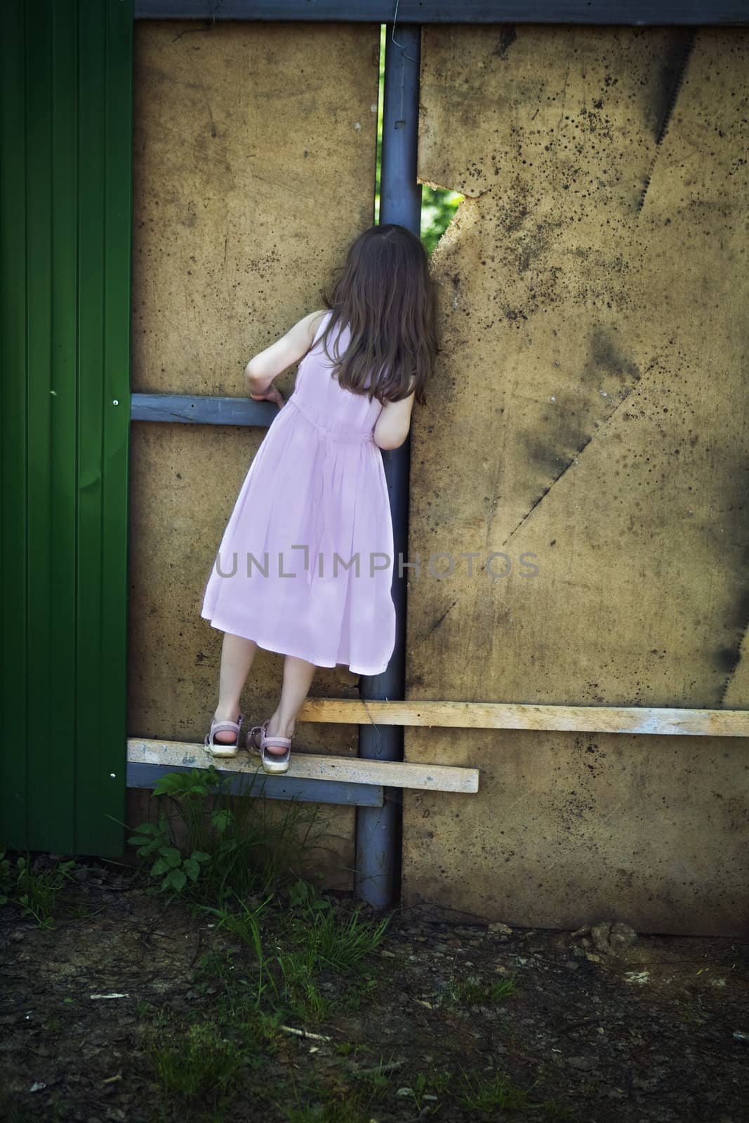 little cute girl five years old looking through hole in wall