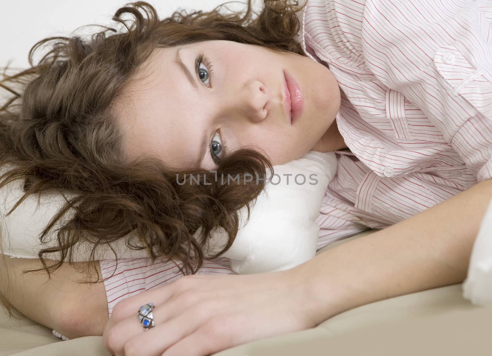 thoughtful brunette curl woman lying on the bed by elenarostunova
