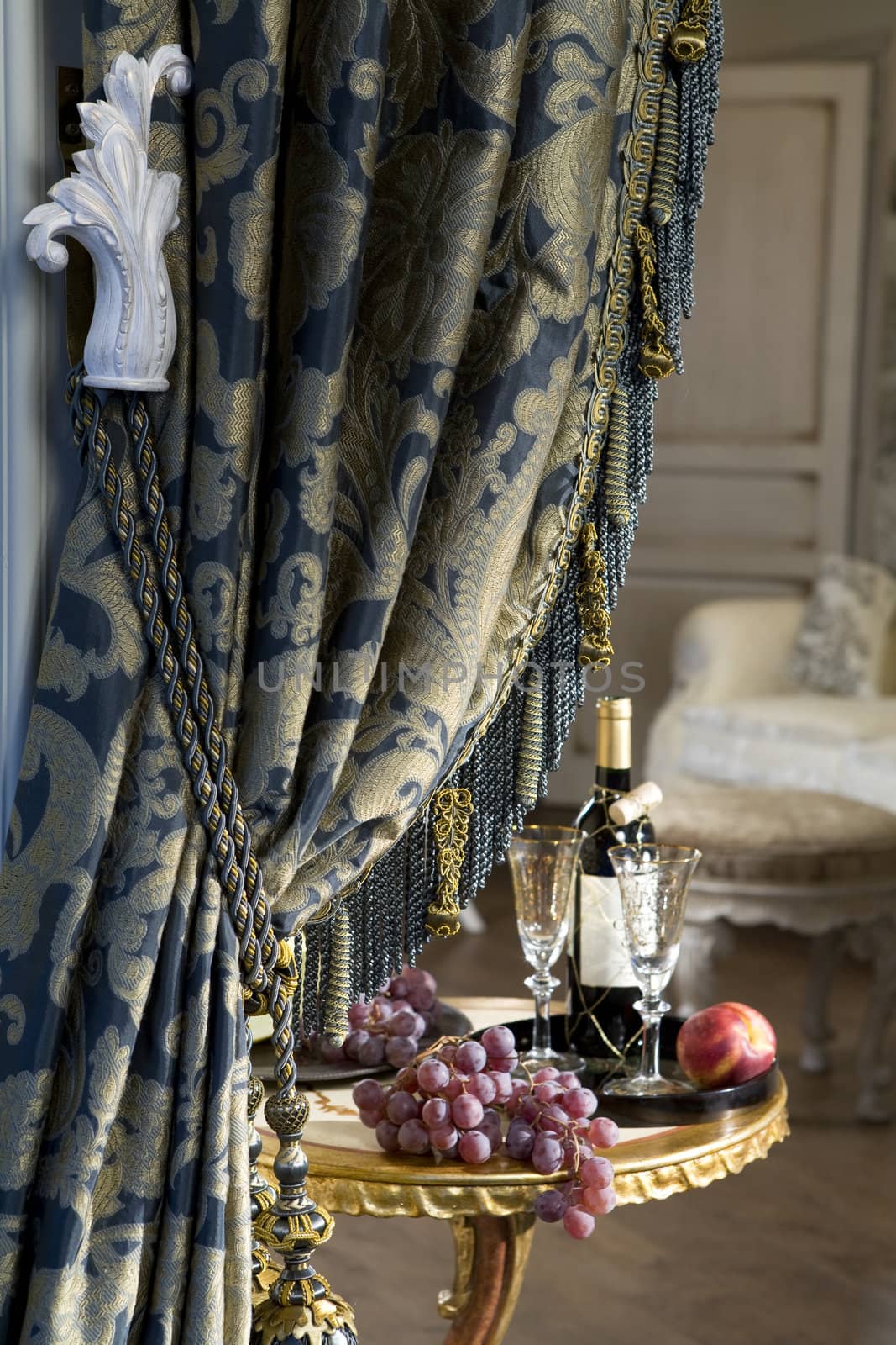 Luxurious curtain from woollen cloth with tassel. Blue and gold. Table with grape. Empire style