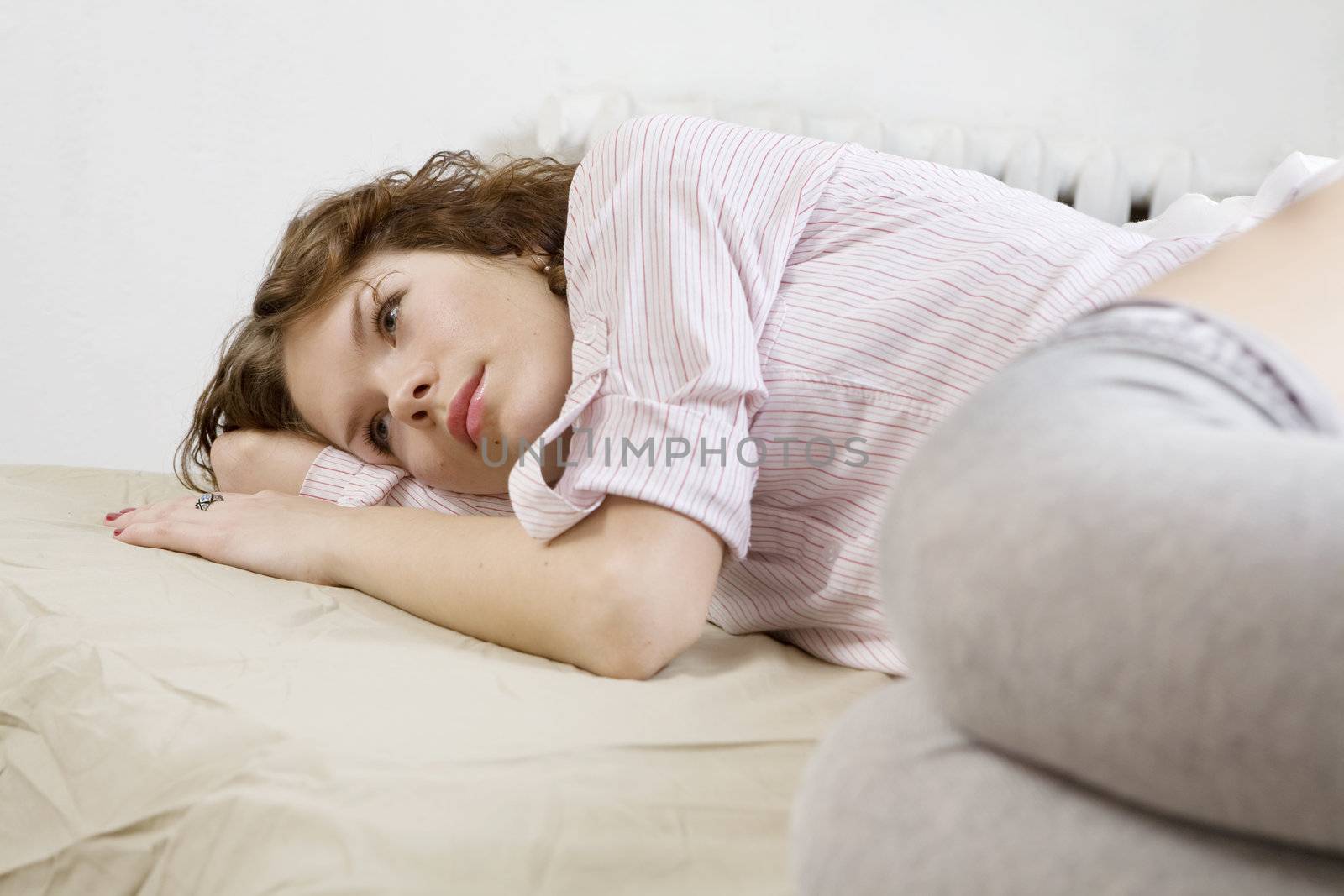 brunette curl woman lying on the bed by elenarostunova
