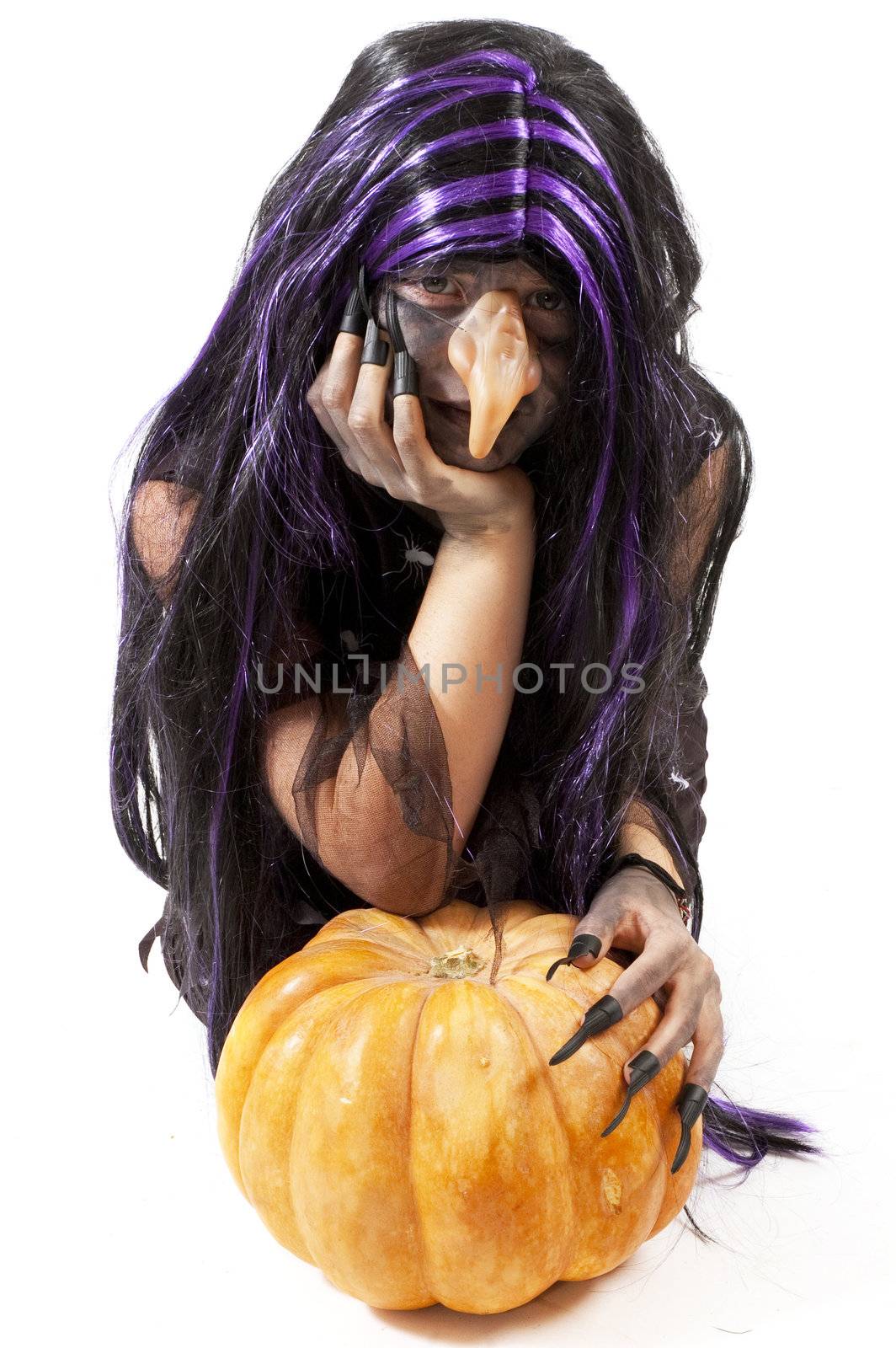 girl dressed up as a witch leaning on a pumpkin