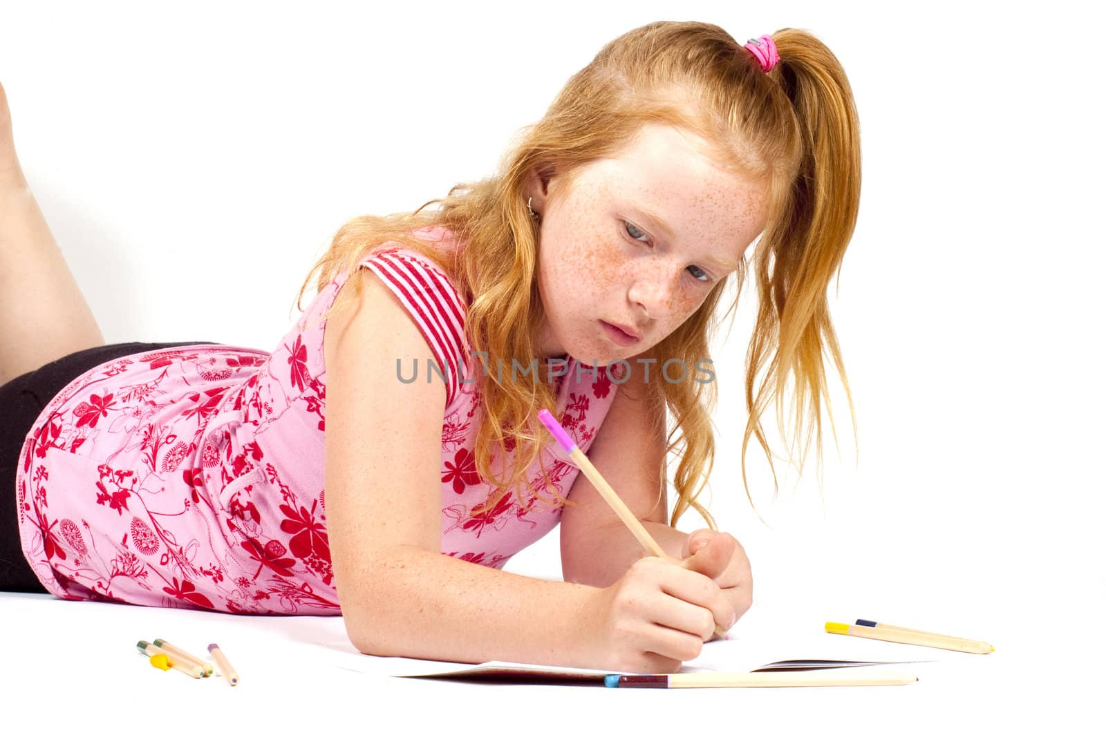 redhead girl is doing her homework isolated on white