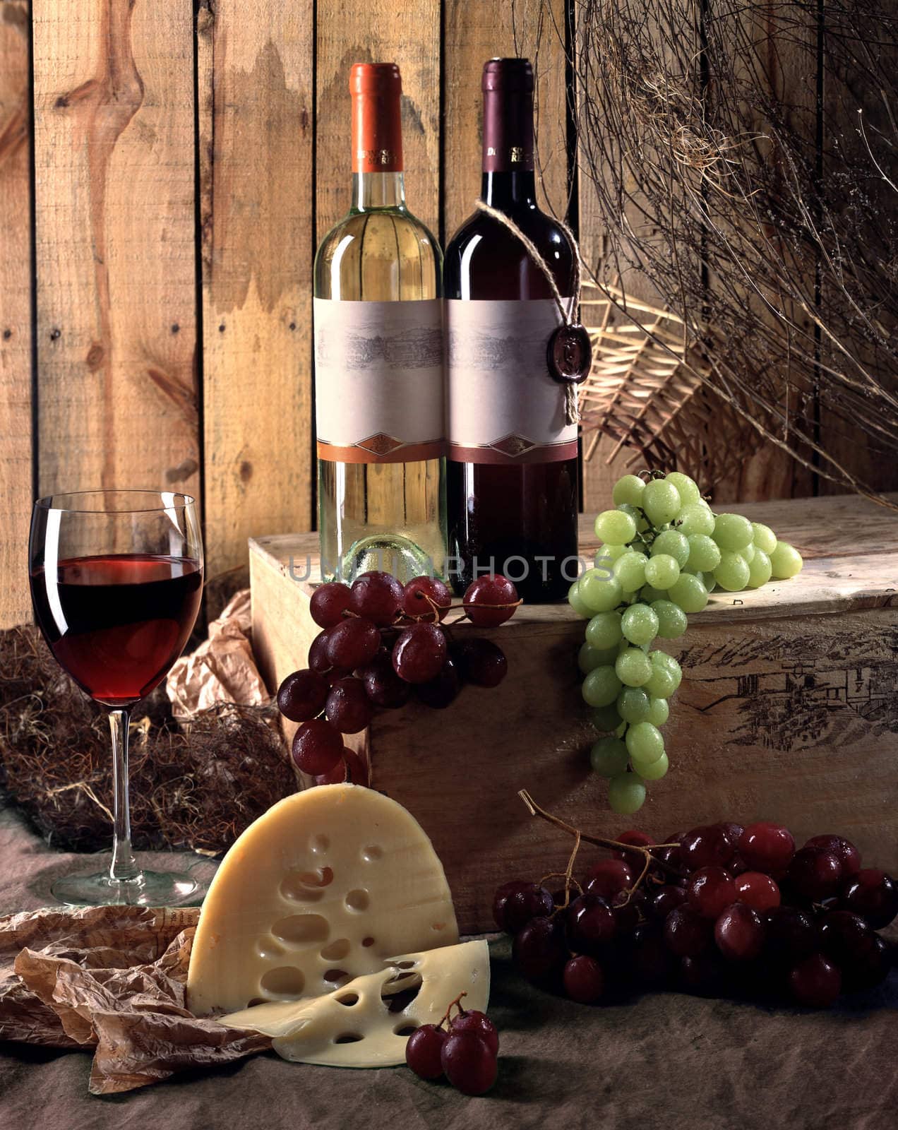 Two bottles of wine with grapes and cheese