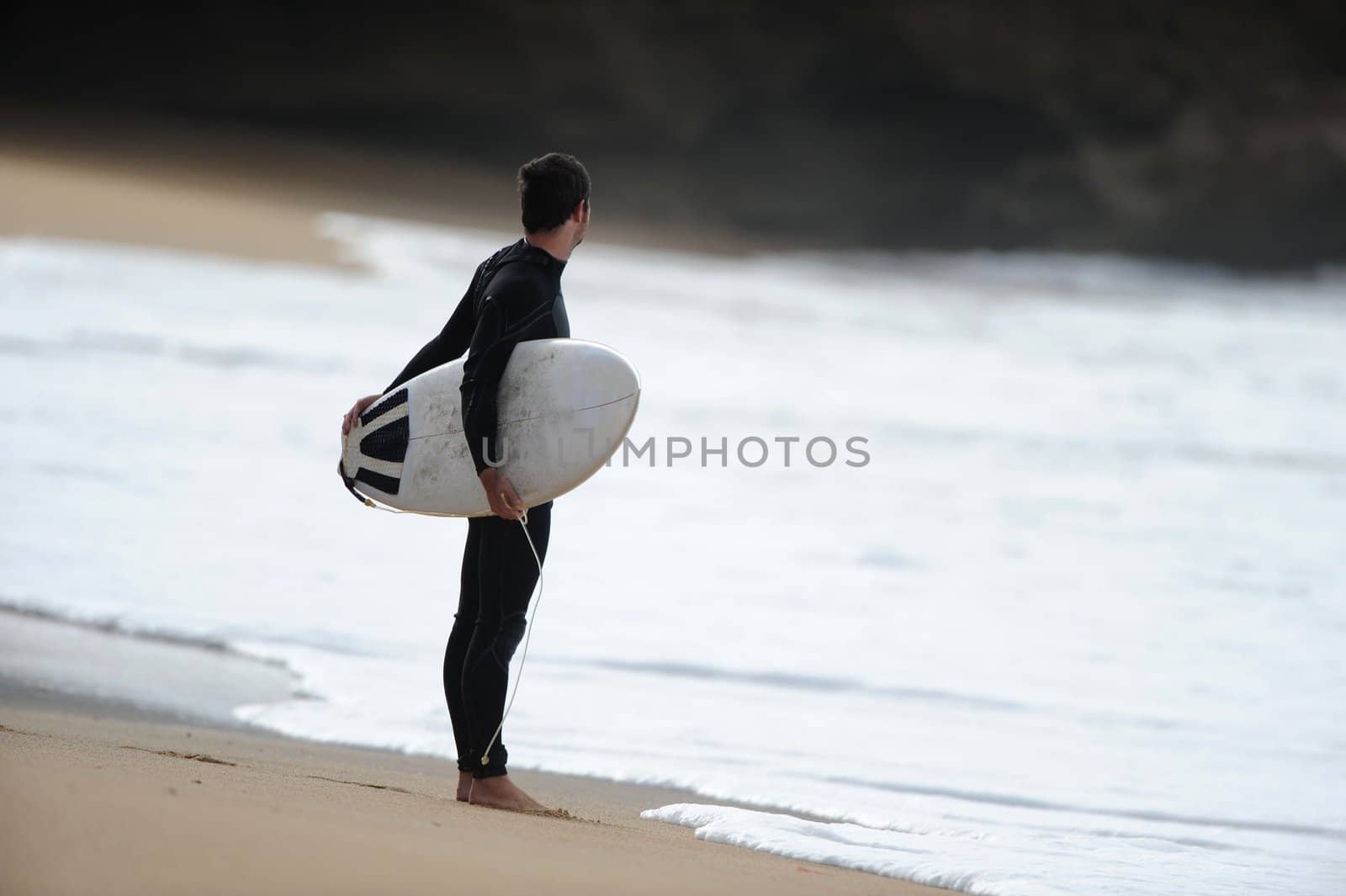 A male sufer checks the waves before heading out into the ocean.