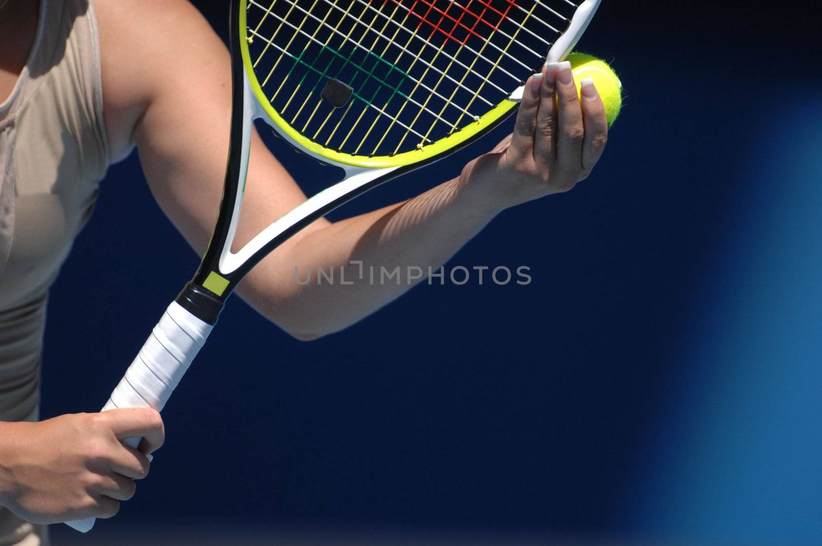 A woman with beautiful hands is holding a tennis ball and raquet preparing for her serve.