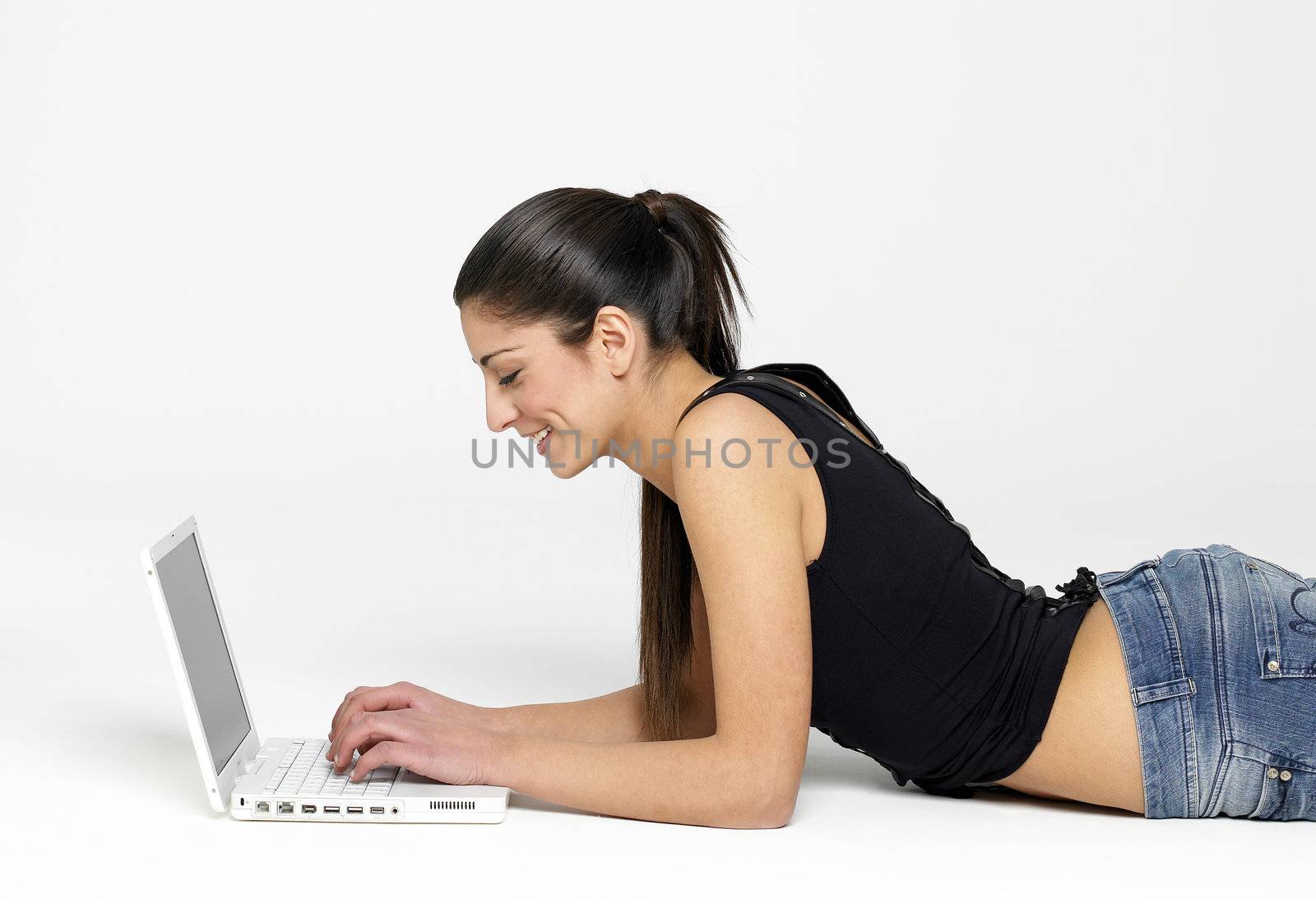 Pretty young girl lying on floor with laptop