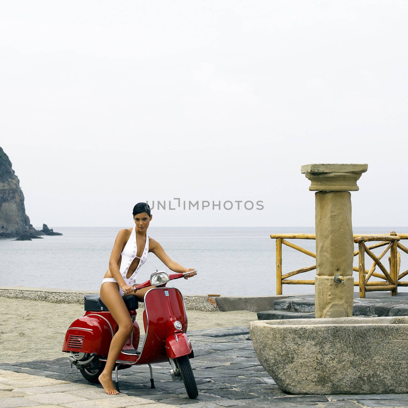Beautiful woman on a scooter near a beach