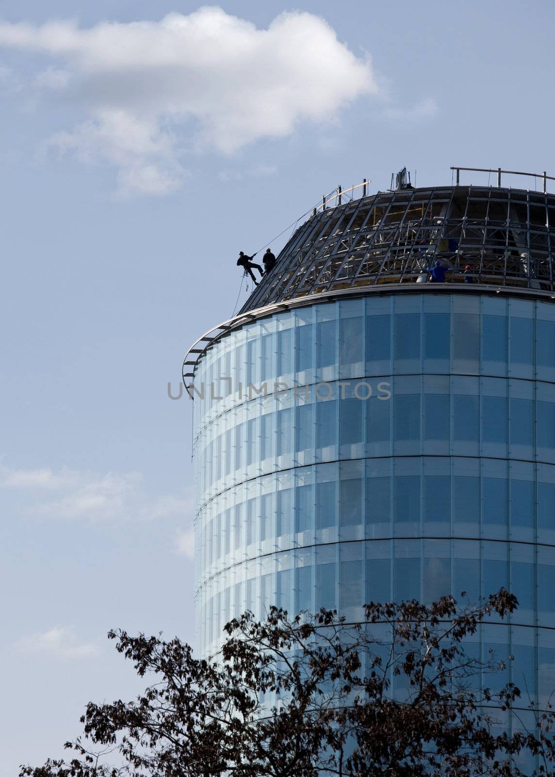 Climber constructor work on blue glass skyscraper 