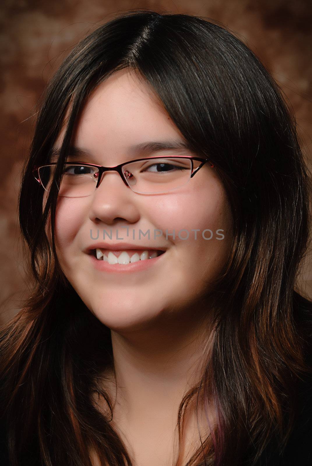 Cute preteen girl with wavy hair is smiling for her portrait