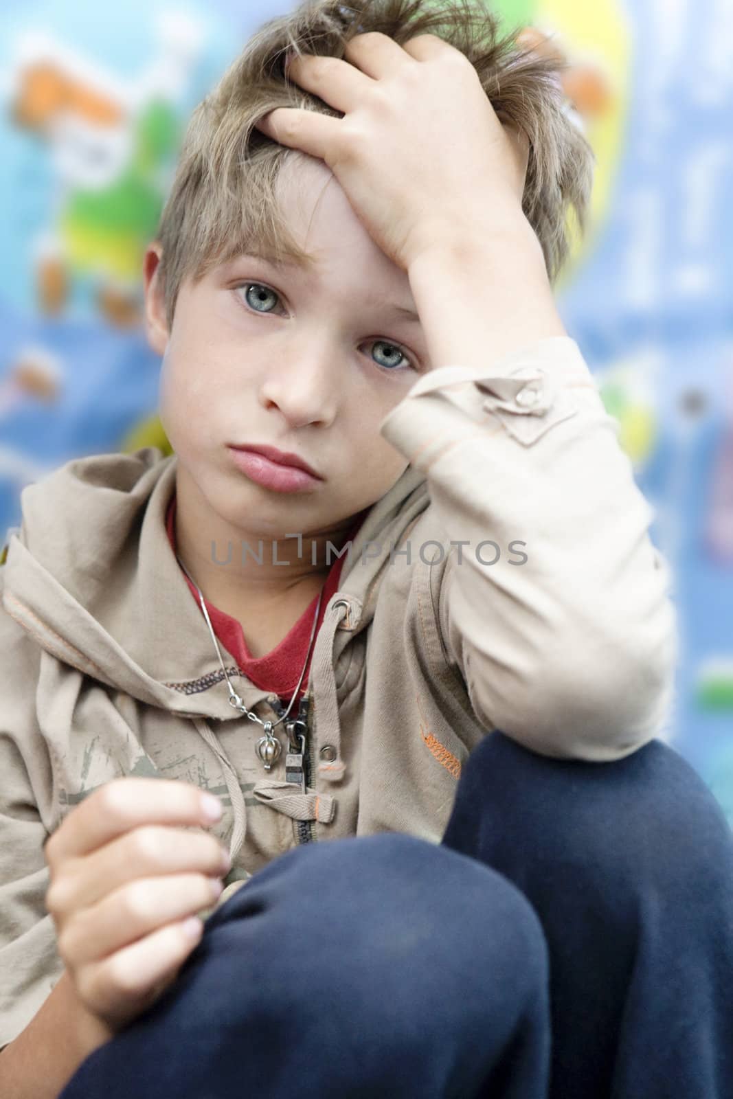 little cute upset boy sitting touch head with hand