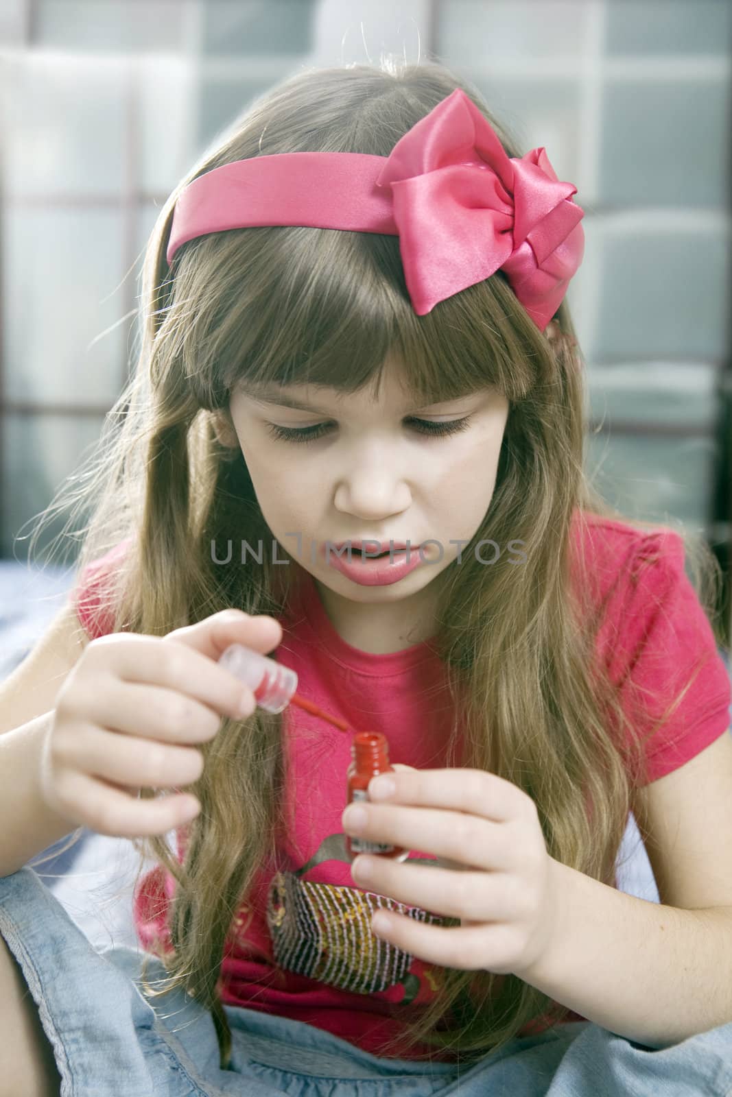 little cute girl  in bow doing make up and painting nail