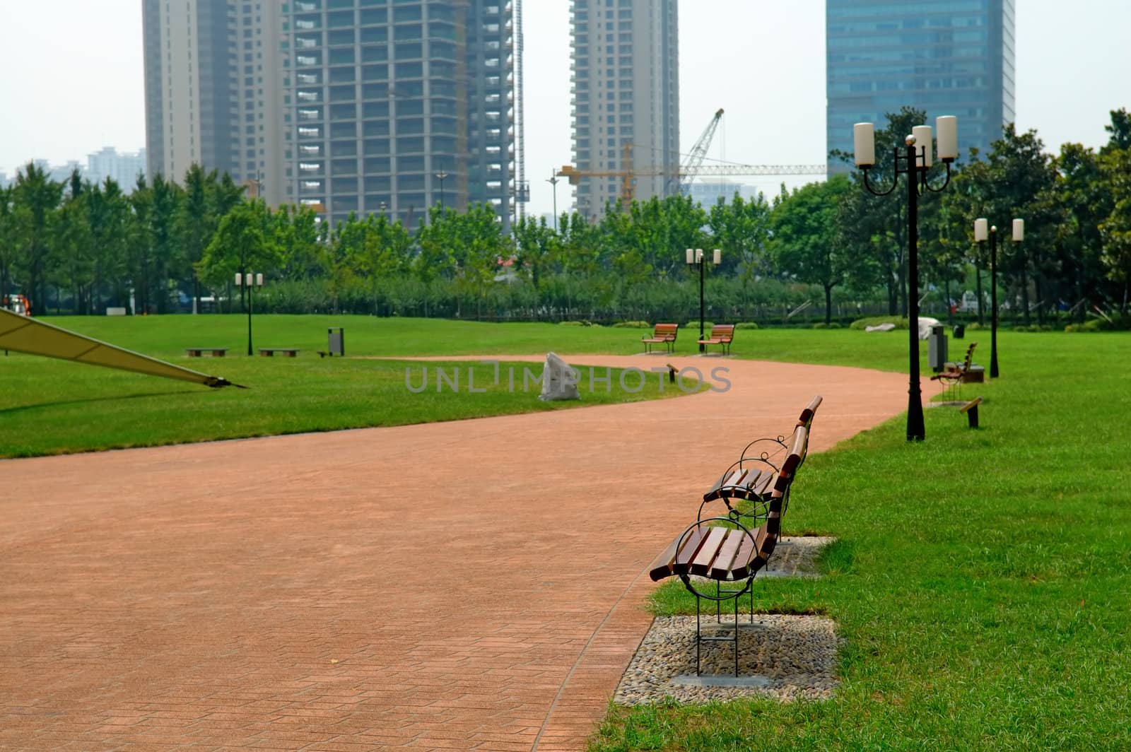 The walk way and bench of city park with building as background