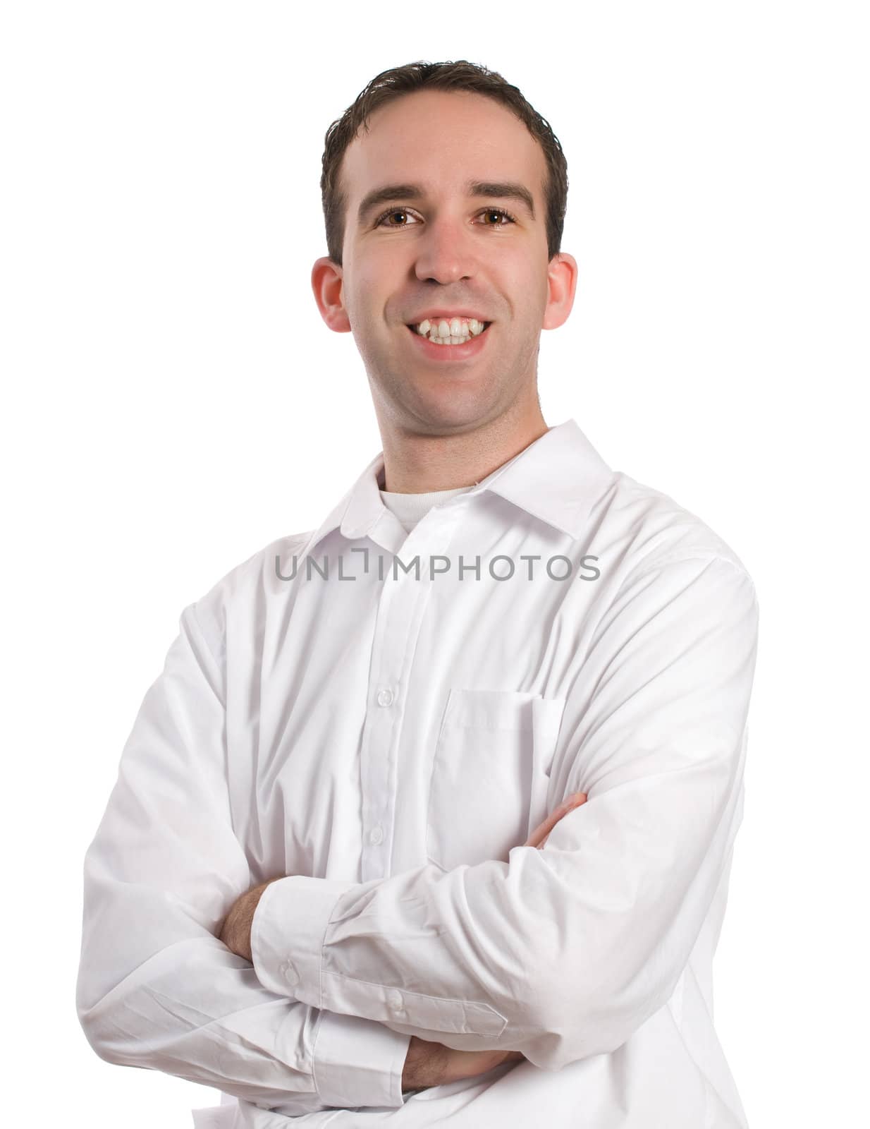 A young man wearing a white dress shirt is standing with his arms crossed and smiling at the camera