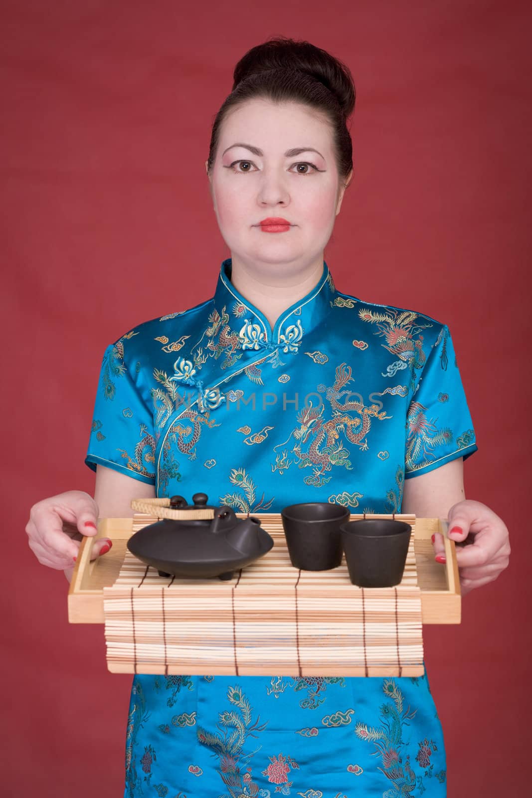 Japanese girl with tea-tray on the red background