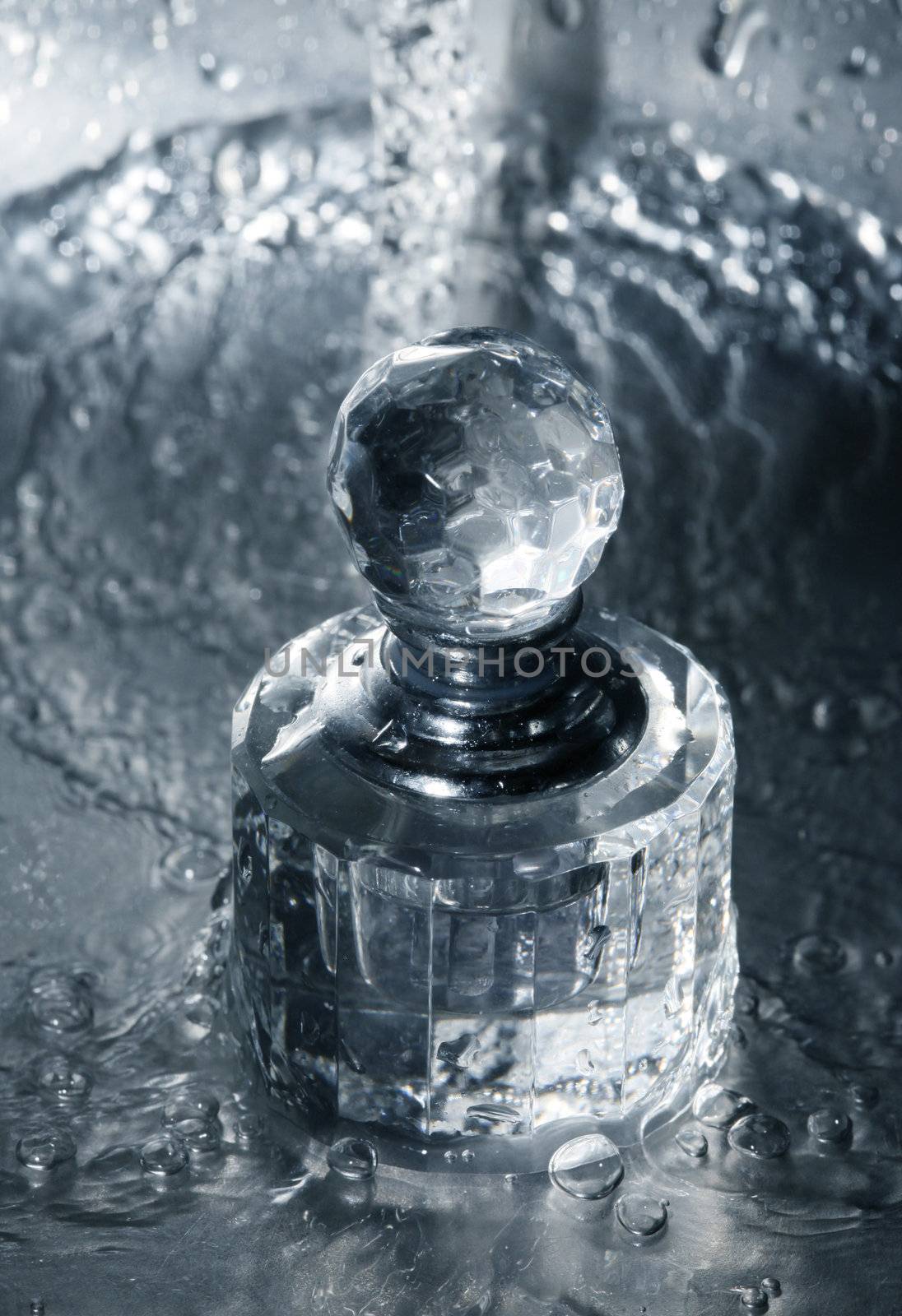 Glass bottle of perfumery in water with drops