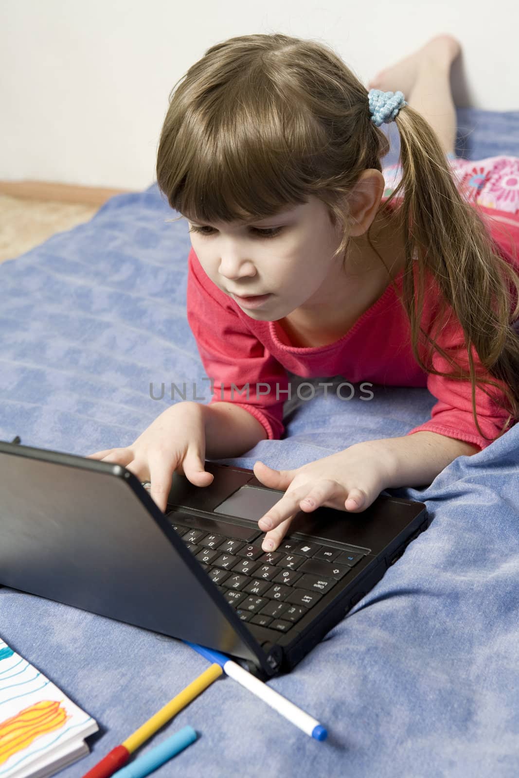 Cute little girl seven years old playing with computer