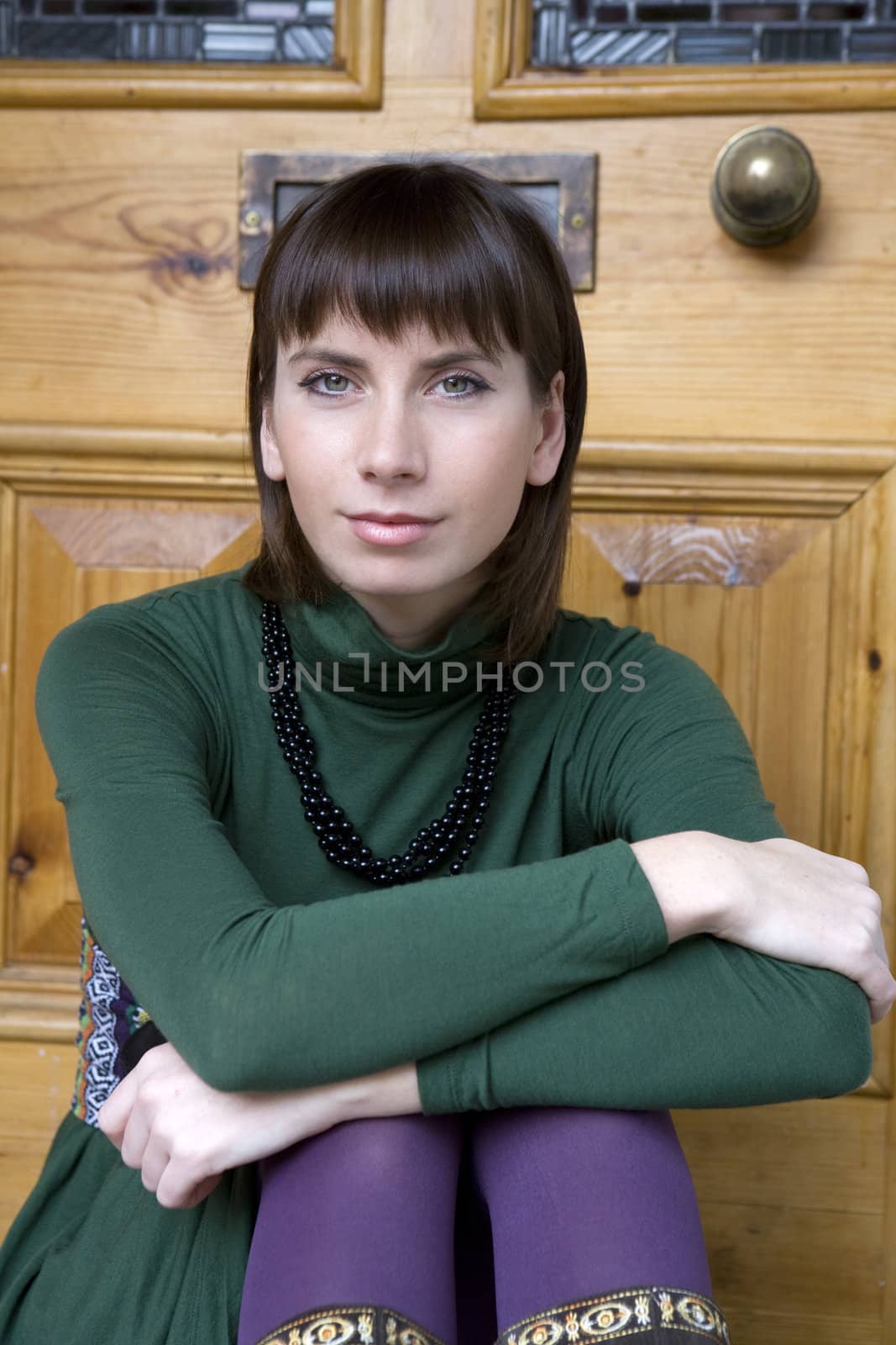 portrait attractive brunette pensive woman wearing green blouse sitting on doorstep

