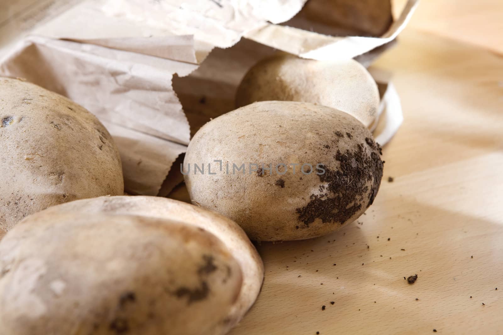 Dirty potato with earth in parcel  on the table. Organic food. microbe in earth. Sharpeness on earth