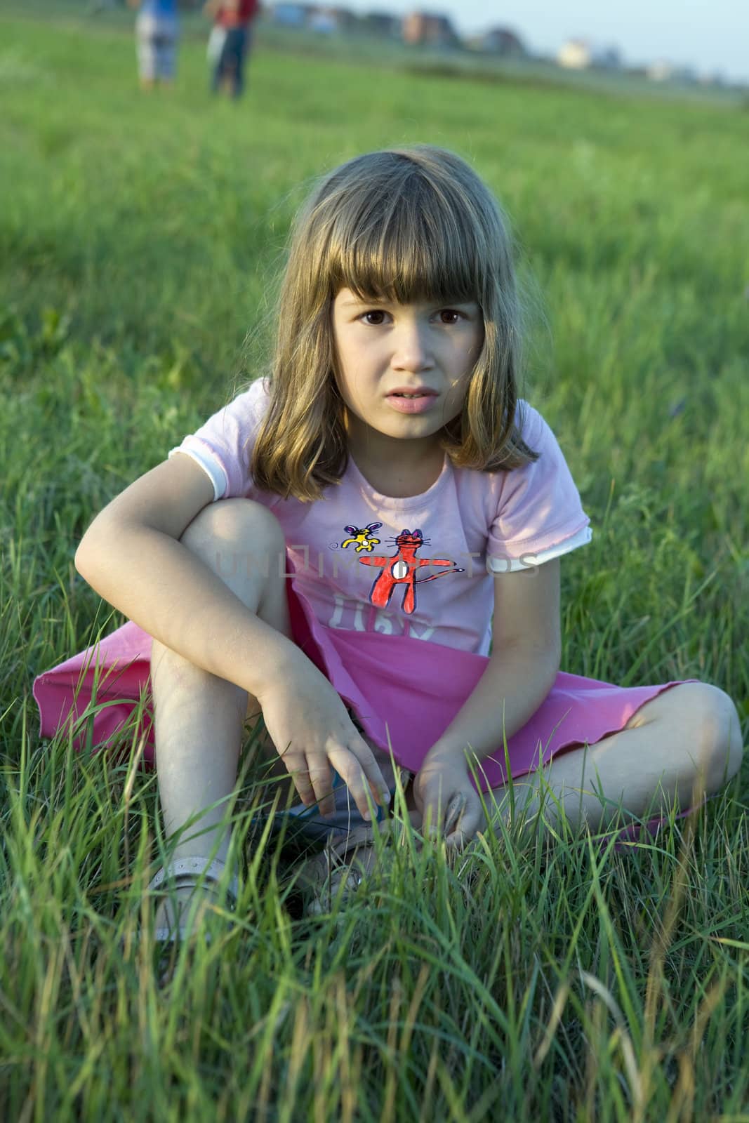 little cute girl sitting in middle of meadow.  by elenarostunova