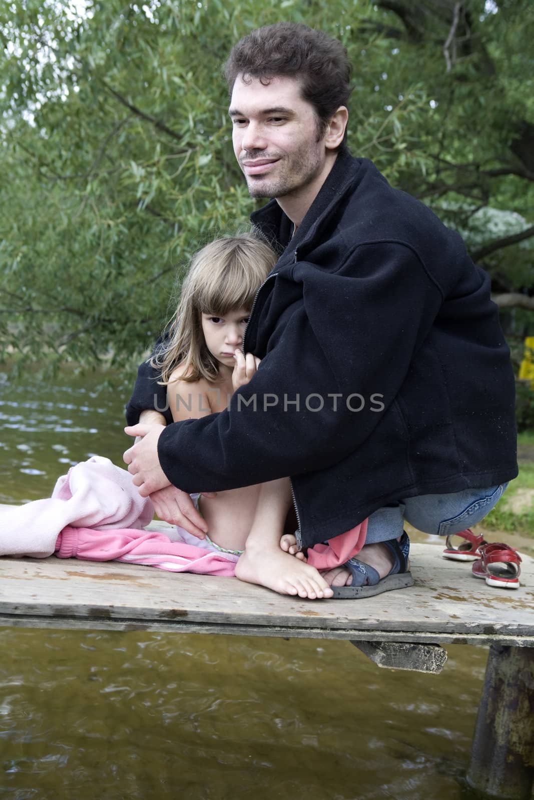 father and frozen daughter on bridge at river after swimming