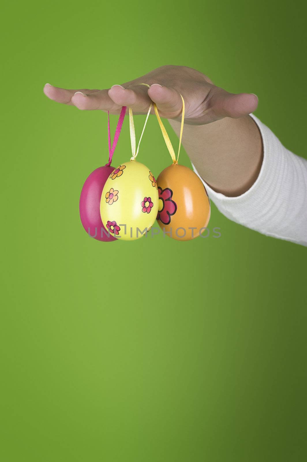 Female hand with easter eggs on a green background