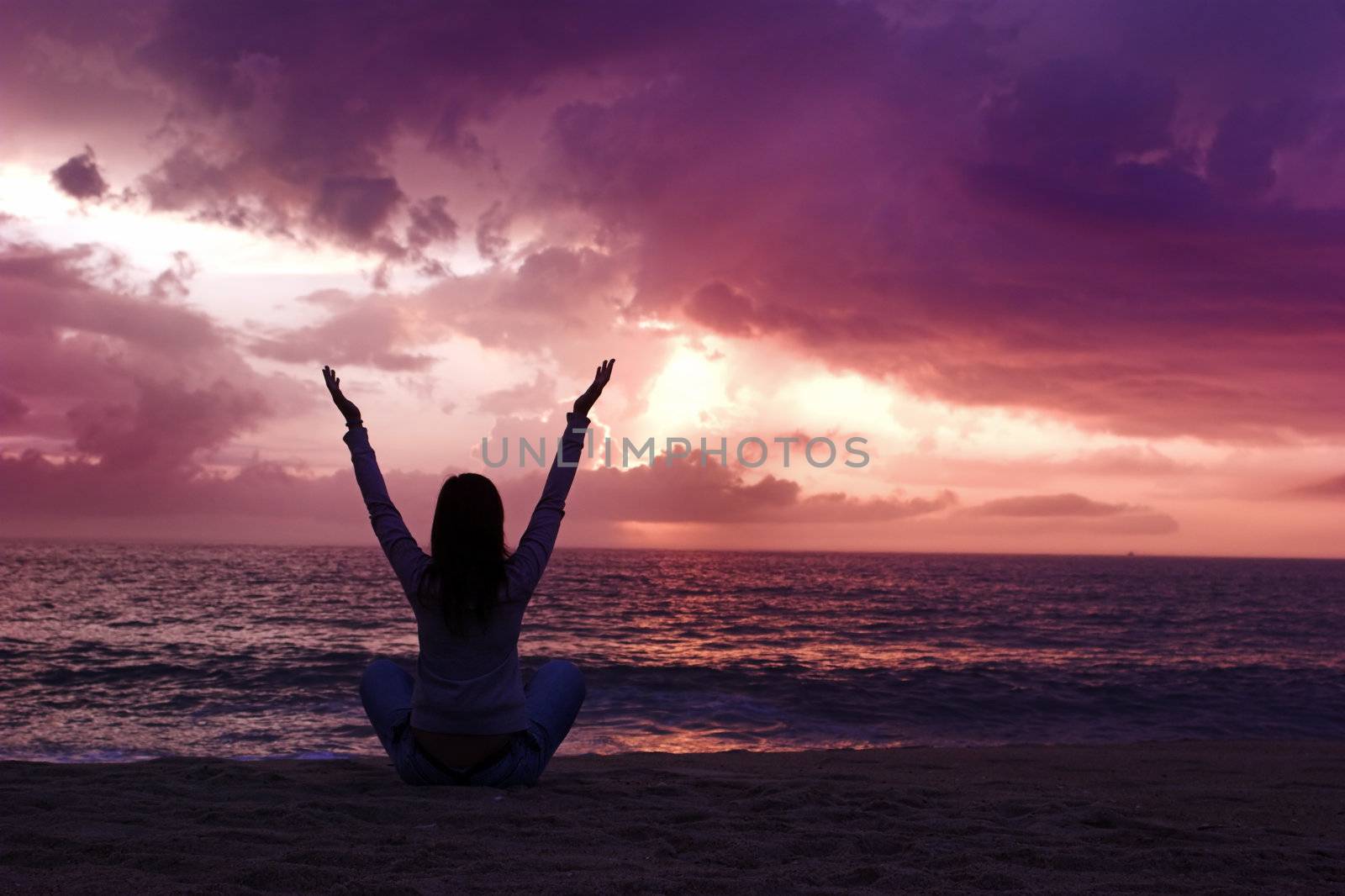 Woman silhouette relaxing on the beach at the sunset