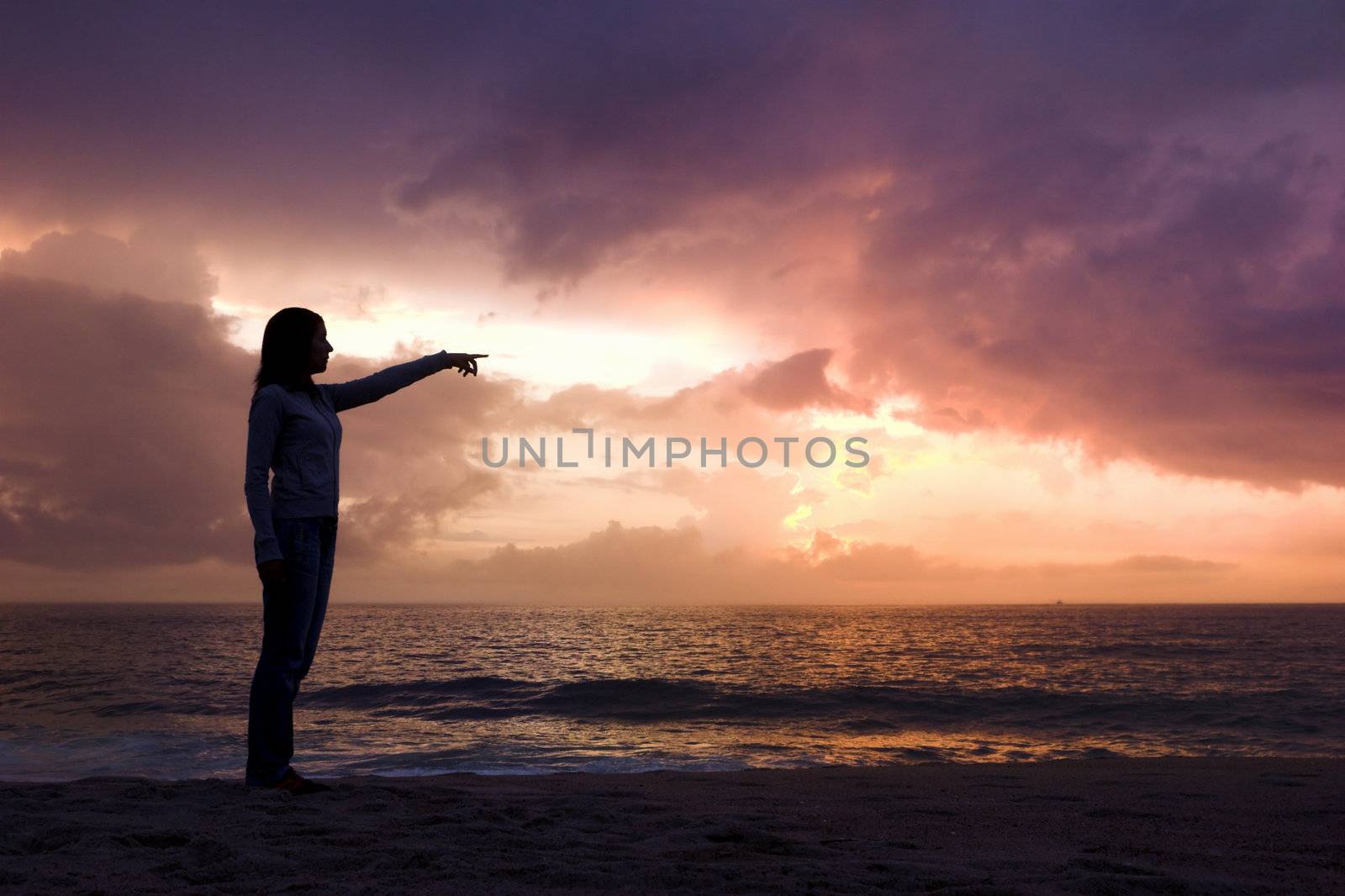 Woman silhouette relaxing on the beach and looking to the sunset