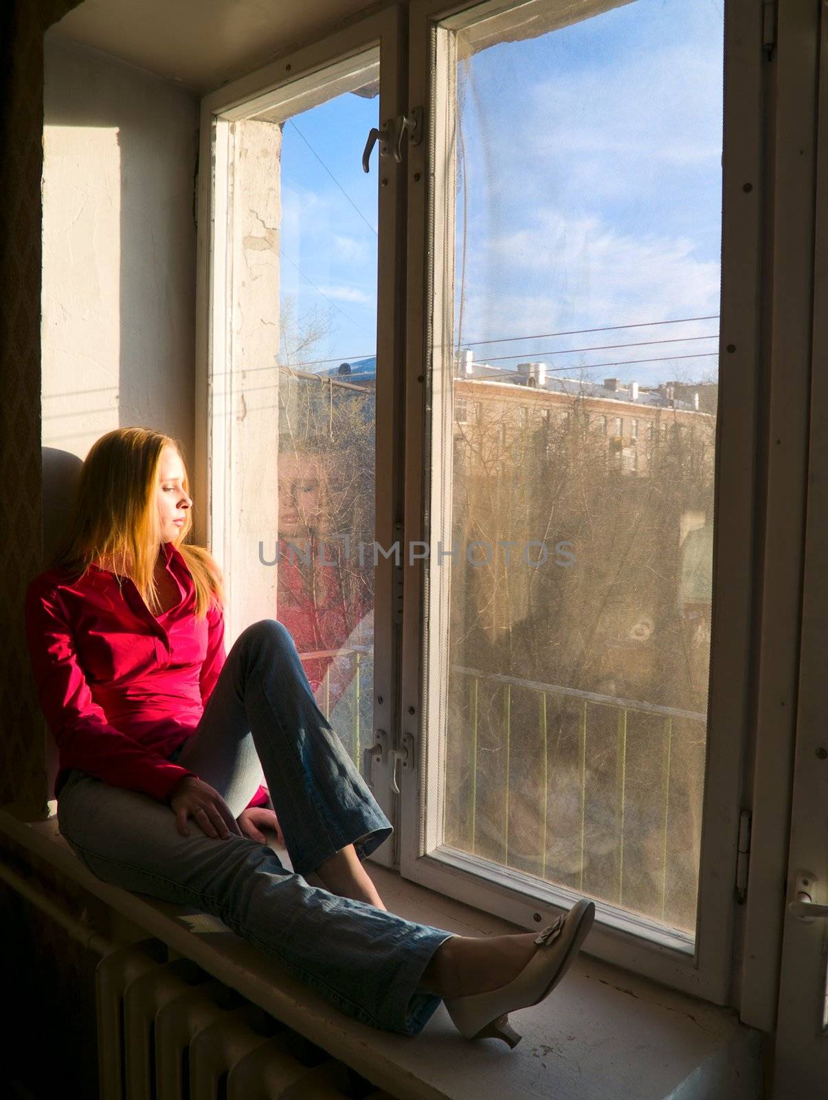 Beauty red-hair girl sitting on window. Thinking and may be dreaming