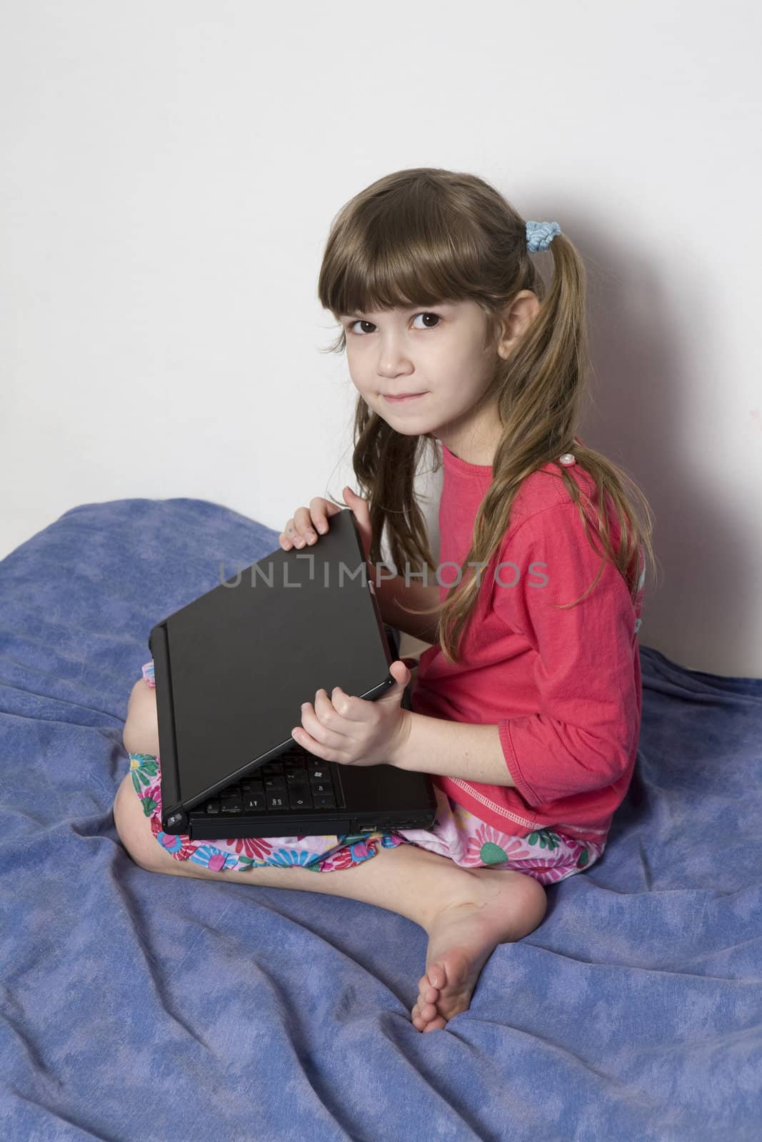 Cute little girl seven years old playing with computer by elenarostunova
