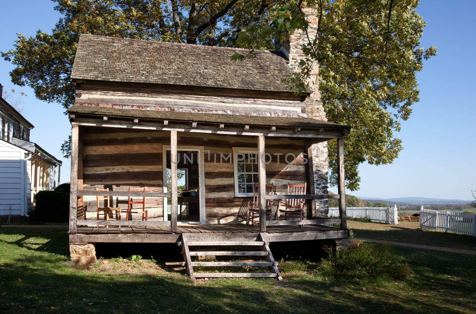 Ancient wooden cabin and porch under large fall tree