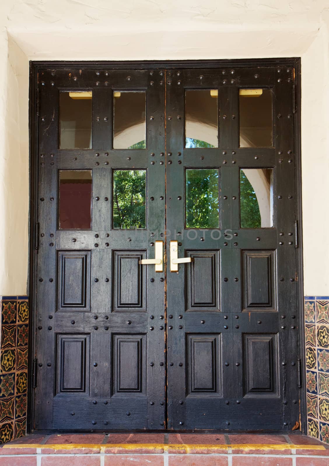 Black Spanish style double doors with tile and stucco walls