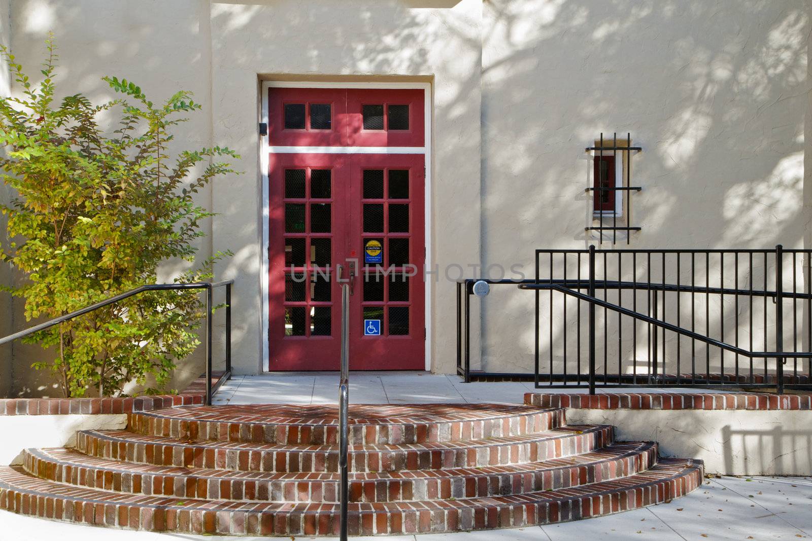 Red Spanish School double doors with brick steps and handicapped assist