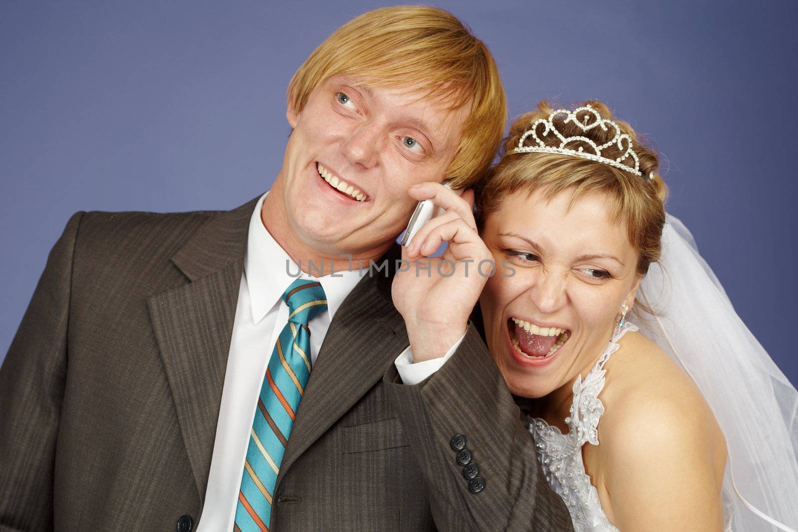 Happy bride and groom is congratulated by phone on blue background
