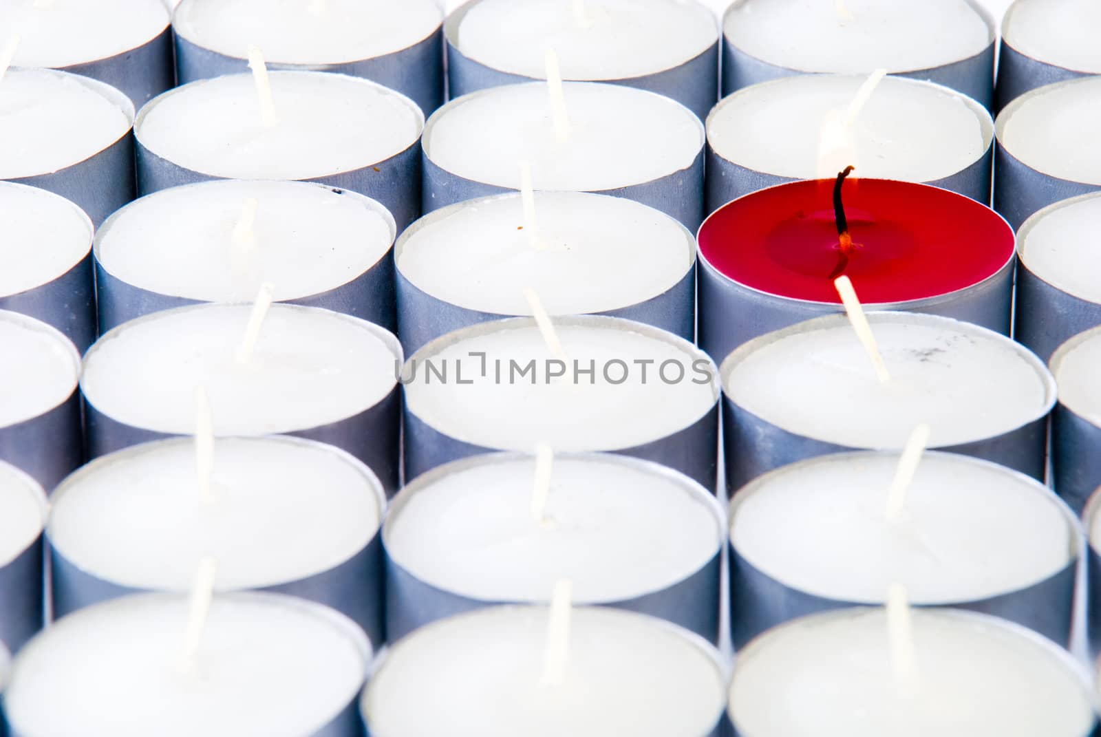 One red candle among lots of white candles