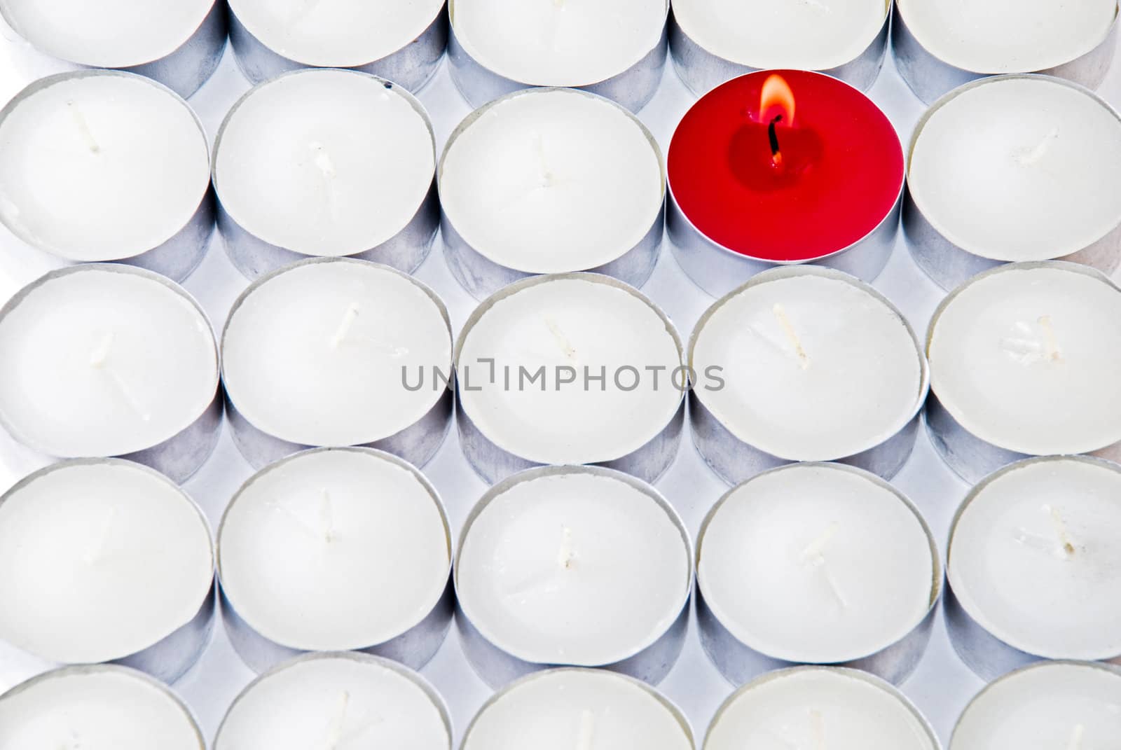 One red candle among lots of white candles