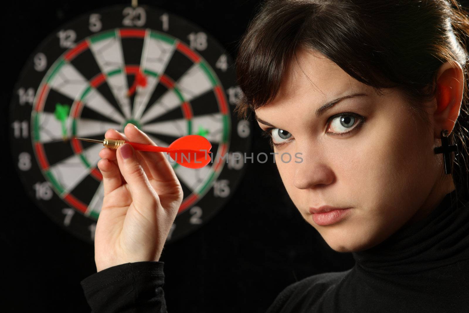 The beautiful girl with darts on a black background