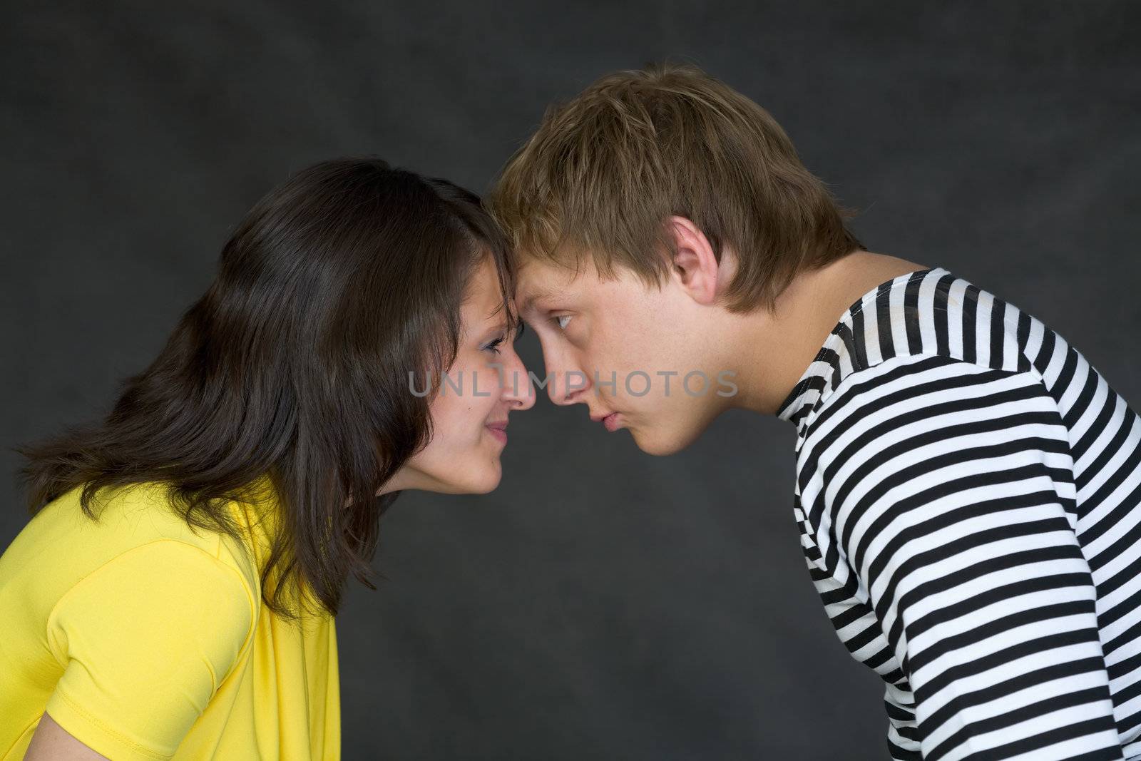 Guy and the girl have faced foreheads on a black background